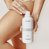 Frau hält den Transparent Lab Hydrating Glycerin Body Cleanser in der Hand vor ihrem Oberschenkel; Fokus auf Produkt und gepflegte Haut.