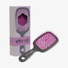 Die grau-rosafarbene Detangling Hair Brush von UNbrush kommt in einer Verpackung mit sechseckigem Muster.