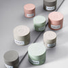 Pastellfarbene Haarpflegetiegel, darunter die Gneiss Moulding Paste von maria nila, auf einer grauen Oberfläche.