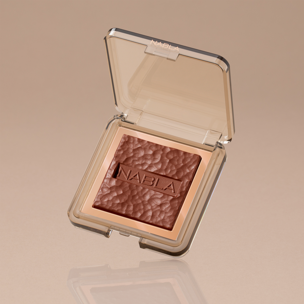 Offenes Kompaktetui mit strukturiertem braunem Skin Bronzing-Puder mit der Prägung „NABLA“, abgebildet auf beigem Hintergrund.