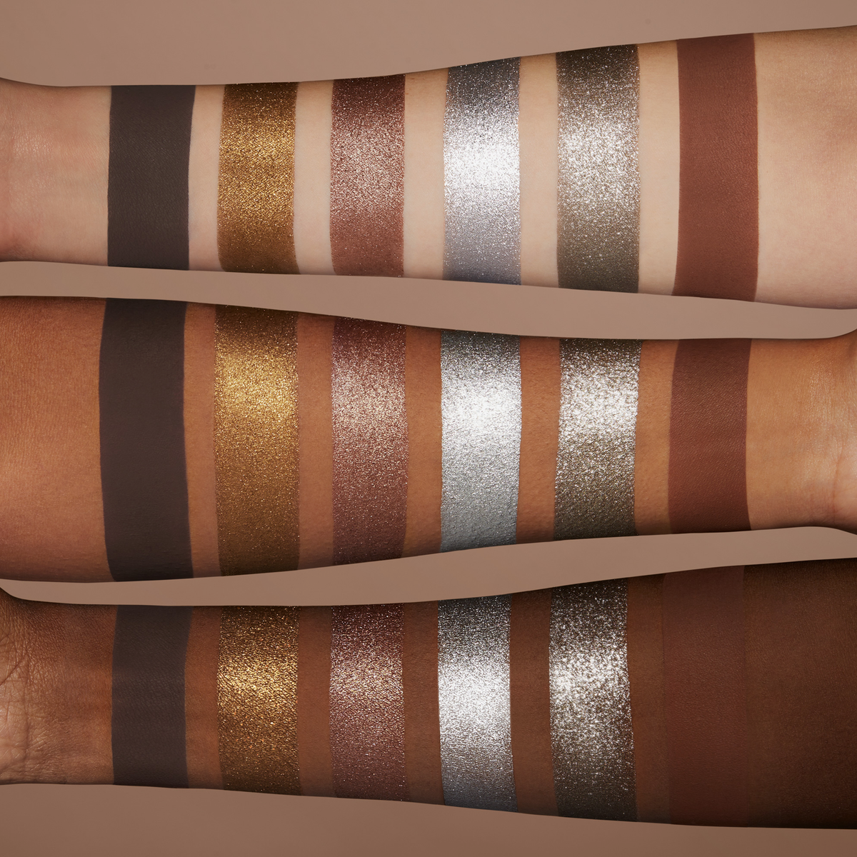 Drei unterschiedlich farbene Unterarme mit je sechs schimmernden und matten Lidschatten-Swatches der NABLA Cutie Palette „Platinum“.