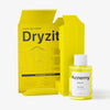 Eine gelbe Flasche Dryzit neben der geöffneten gelben Verpackung vor weißem Hintergrund