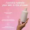In der Hand hält das Bali Body Shower Oil vor rosa Hintergrund; daneben Vorteile des Produkts
