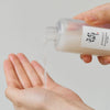 Eine Hand gießt die Glow Repleneshing Rice Milk in die andere Handfläche.