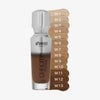 Eine halb transparente halb silberne Flasche Chroma Cover Foundation Luminous neben Farbmustern der W-Shades.