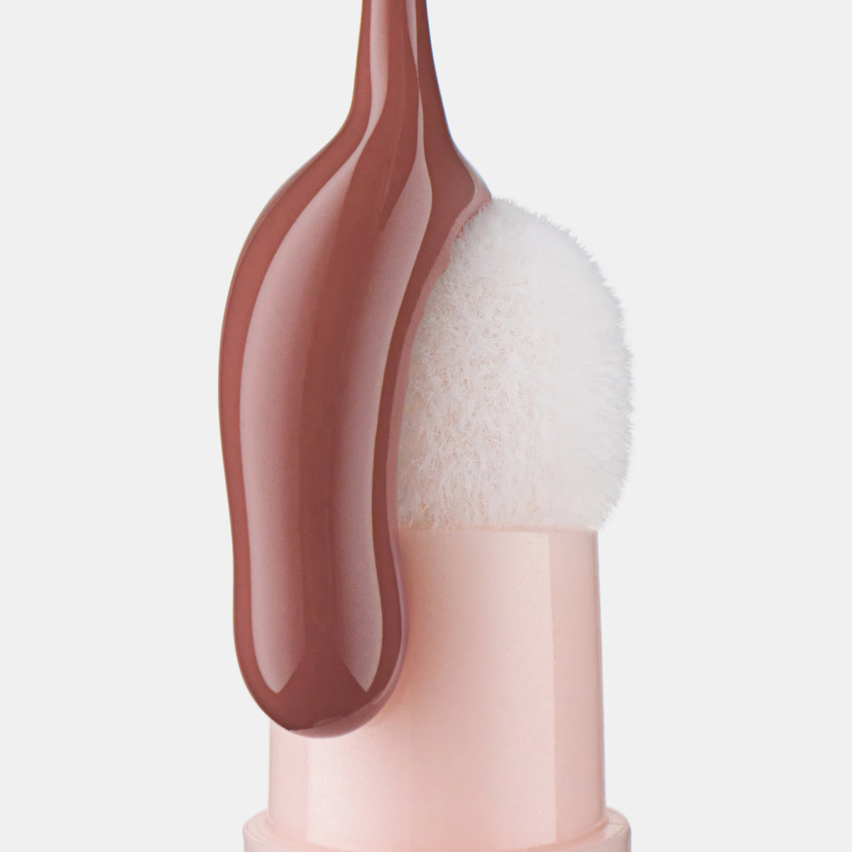 Braunes Lip Oil von Catrice läuft über den weißen Schwamm-Applikator des Colour Cushion Juicy Lip Oils in Nahaufnahme.