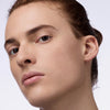 Nahaufnahme einer Person mit braunem Haar und braunen Augen die den Instant Bright Serum Concealer 033C auf der Haut präsentiert.