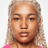 Geteiltes Gesicht einer jungen Frau mit mittlerem Hautton zeigt links natürliche Haut und rechts perfektioniertes Hautbild mit MAGIC FILTER Glow Booster 40 Tan.