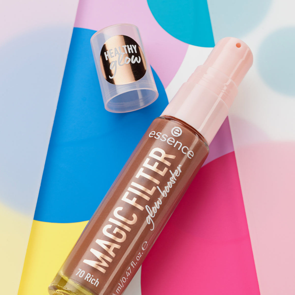 Eine Flasche MAGIC FILTER Glow Booster 70 Rich liegt auf einem bunten geometrischen Hintergrund.