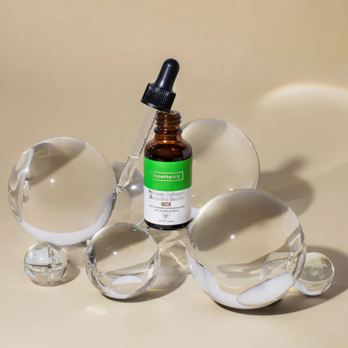 PolyPep Collagen Boosting Serum S8 PRO in einer Tropfflasche mit schwarzer Pipette, dargestellt mit klaren Glaskugeln auf einer beigen Oberfläche.