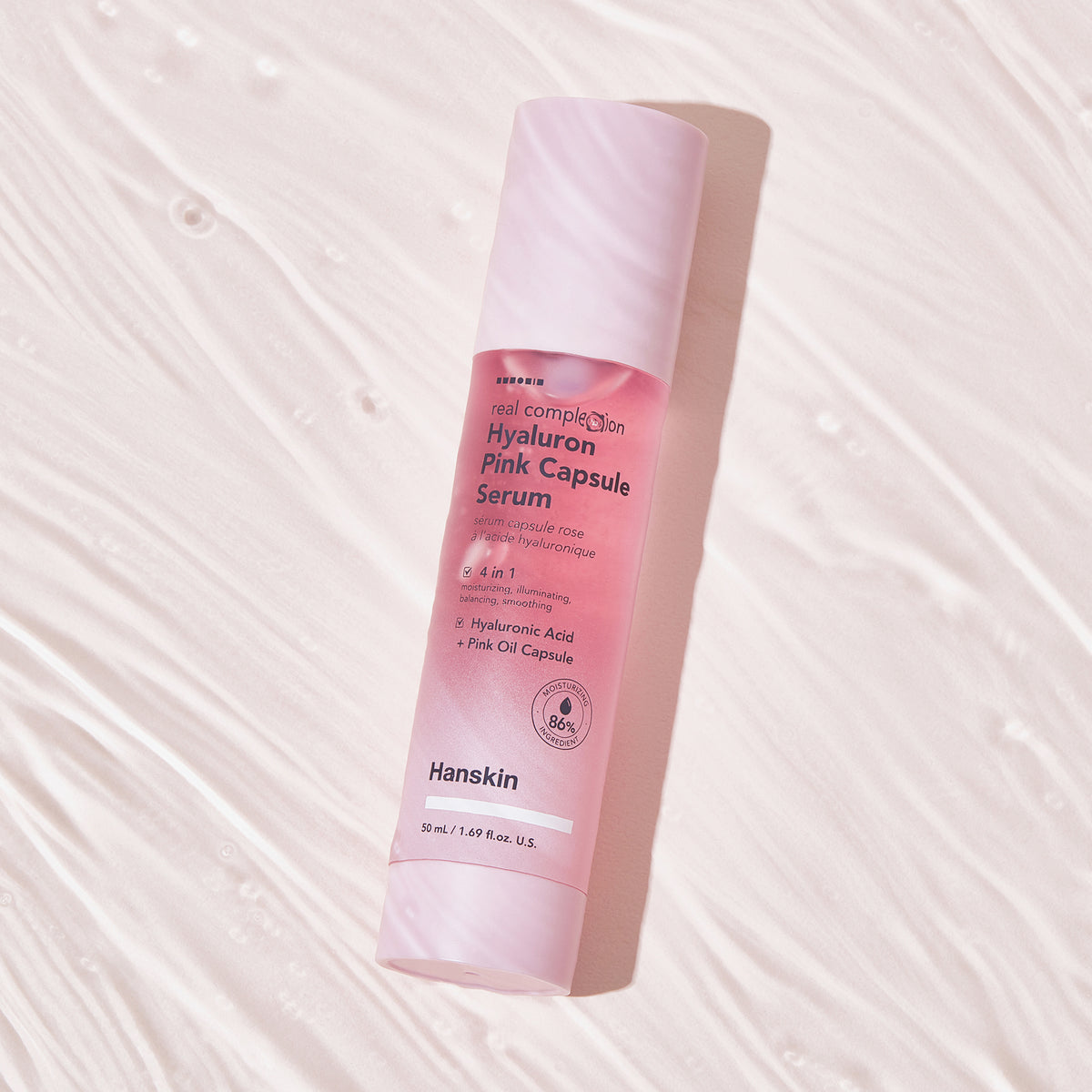 Eine rosa Flasche Real Complexion Hyaluron Pink Capsule Serum, präsentiert auf einer strukturierten weißen Oberfläche.