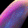 Nahaufnahme einer Fingerspitze, die in den Opal Moonstone Loose Multichrome Eyeshadow Lazy Boney getaucht wurde und rosa-lila glitzert.