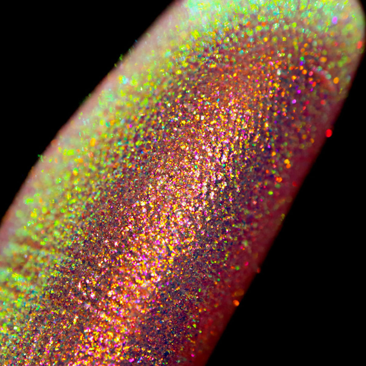 Nahaufnahme einer Fingerspitze, die in den Opal Moonstone Loose Multichrome Eyeshadow Sassy Pants getaucht wurde und gelb-grün und rosa-bronze glitzert.