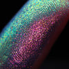 Nahaufnahme einer Fingerspitze, die in den Opal Moonstone Loose Multichrome Eyeshadow Sleepy Head getaucht wurde und blau-violett glitzert.