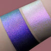 Zwei schimmernde Muster des Opal Multichrome Loose Eyeshadow Night Kiss mit unterschiedlichen Grundierungen; eins mit der Black Base (lila), eins mit der Fix Potion (hellviolett-rosa).