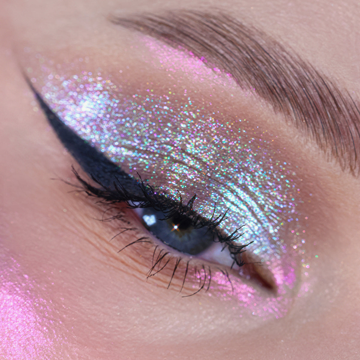 Nahaufnahme eines Auges mit dramatischem Eyeliner und pink-opal-türkis schimmerndem Opal Multichrome Loose Eyeshadow in Velvet Dreams.