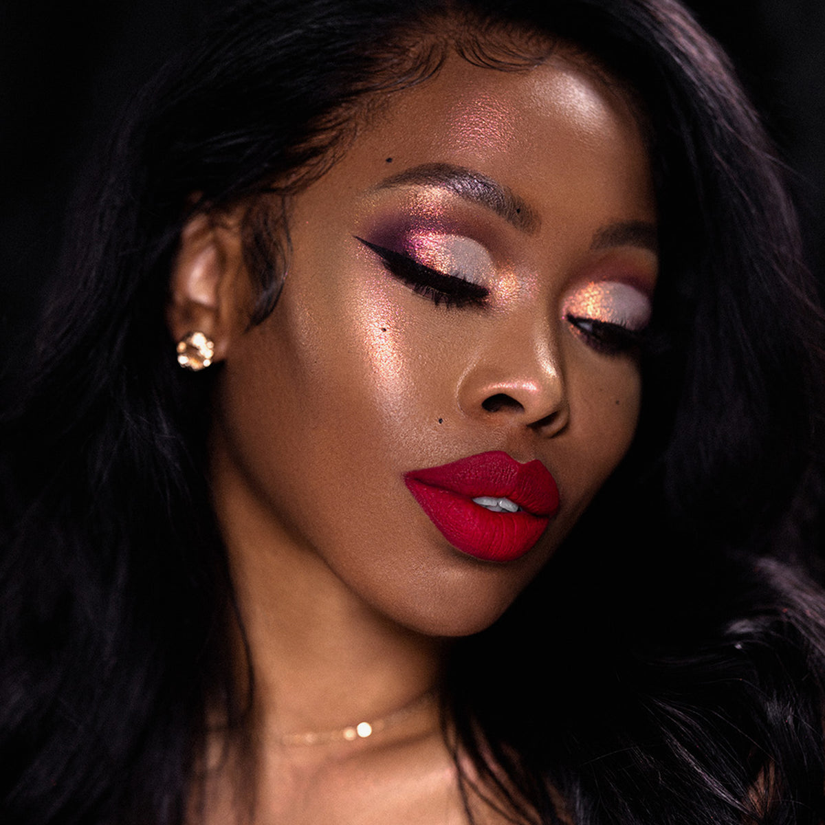 Frau mit langem dunklem Haar, kräftigen roten Lippen und schimmerndem gold- und rosafarbenem Augen-Make-up, kreiert mit Opal Shadow Potion Silky Gel Eyeshadow, Augen geschlossen.