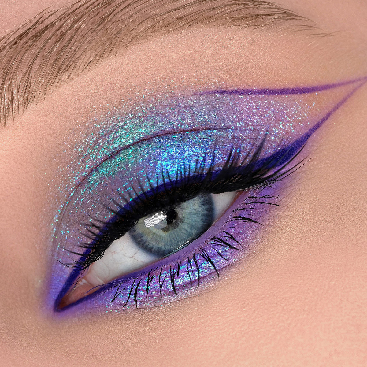 Nahaufnahme eines Auges mit dramatischem Eyeliner und blau-lila schimmerndem Opal Shadow Potion Silky Gel Eyeshadow in Dreamer.