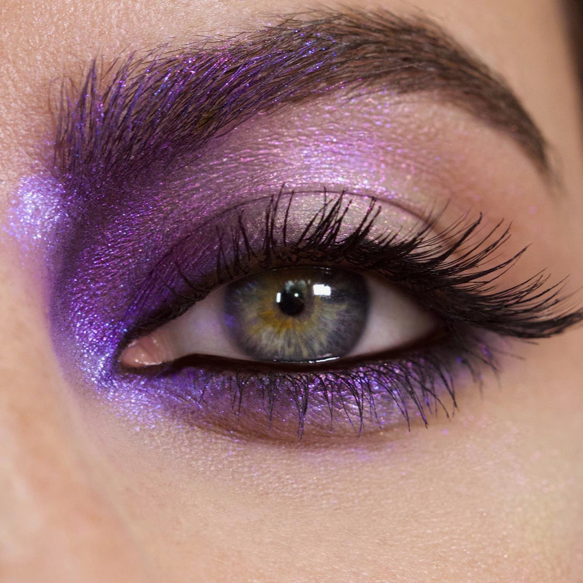 Nahaufnahme eines Auges mit dramatischem Eyeliner und lila schimmerndem Opal Shadow Potion Silky Gel Eyeshadow in Insomnia.