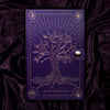 Violette Außenverpackung der Lethal Cosmetics Spellcraft Pressed Powder Palette mit goldgeprägten Baum auf einem dazu passenden violetten Samthintergrund.