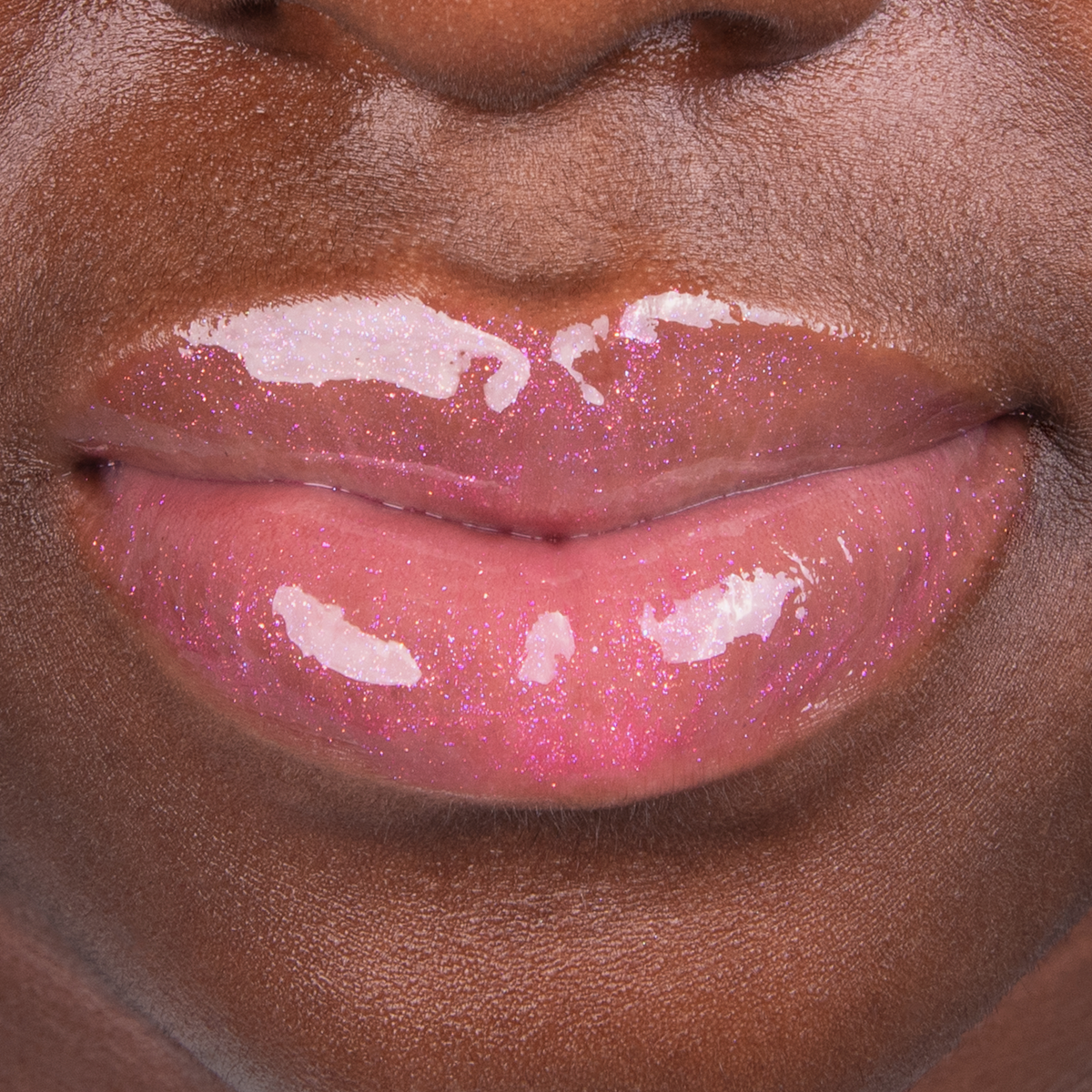 Nahaufnahme von glänzenden, rosafarbenen Glitzerlippen auf dunkler Haut mit dem The SpongeBob Movie Lip Gloss 'Patrick Star' von Lethal Cosmetics.