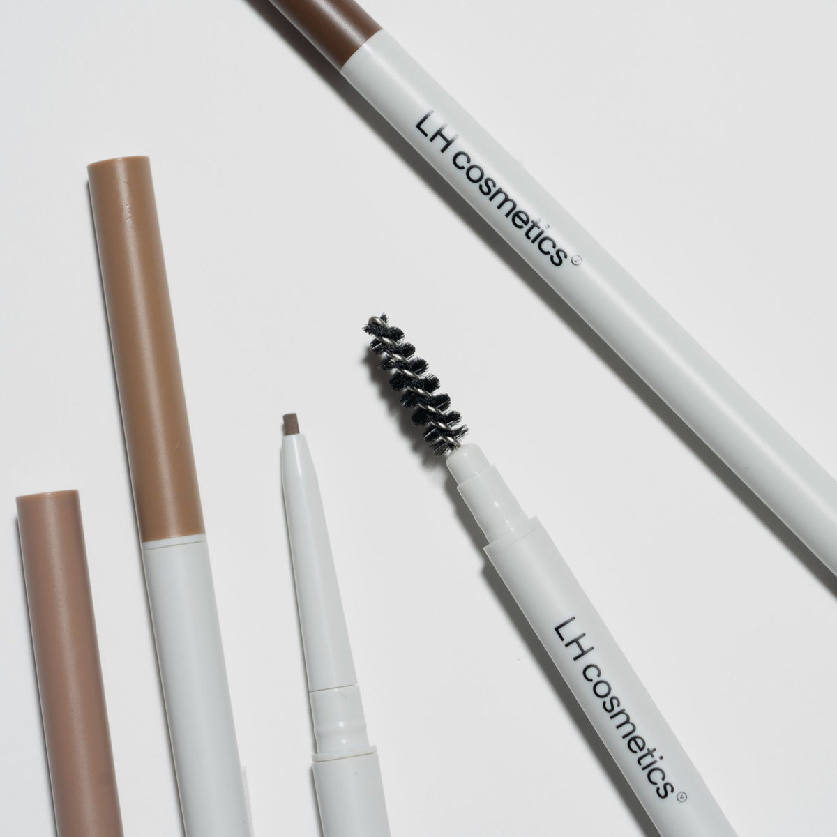 Mehrere Infinity Brow Pens von LH Cosmetics liegen auf weißer Oberfläche.