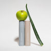 Zwei Flaschen „On set – Subtle glow setting spray“ von LH Cosmetics werden mit einem grünen Apfel und einem Aloe-Vera-Blatt vor einem weißen Hintergrund präsentiert.