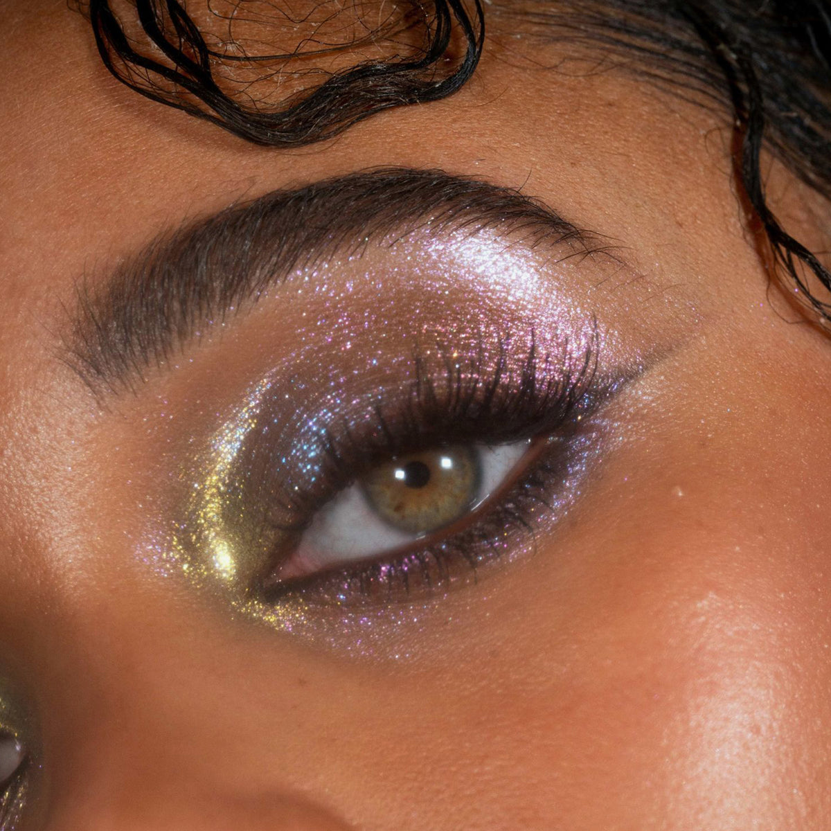 Nahaufnahme eines Auges mit kräftigem, schimmerndem lila und goldenem Lidschatten aus der Siren Song Palette von LH Cosmetics.