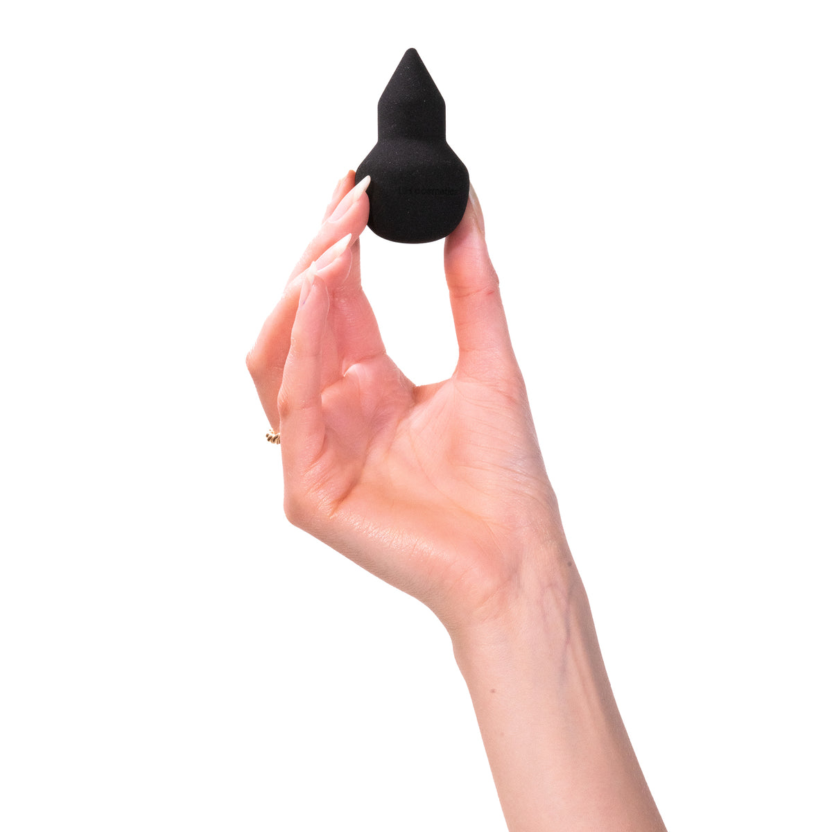 Eine Hand hält „The Sponge“ von LH Cosmetics, ein schwarzes, spitzes Make-up-Tool, vor einem weißen Hintergrund.