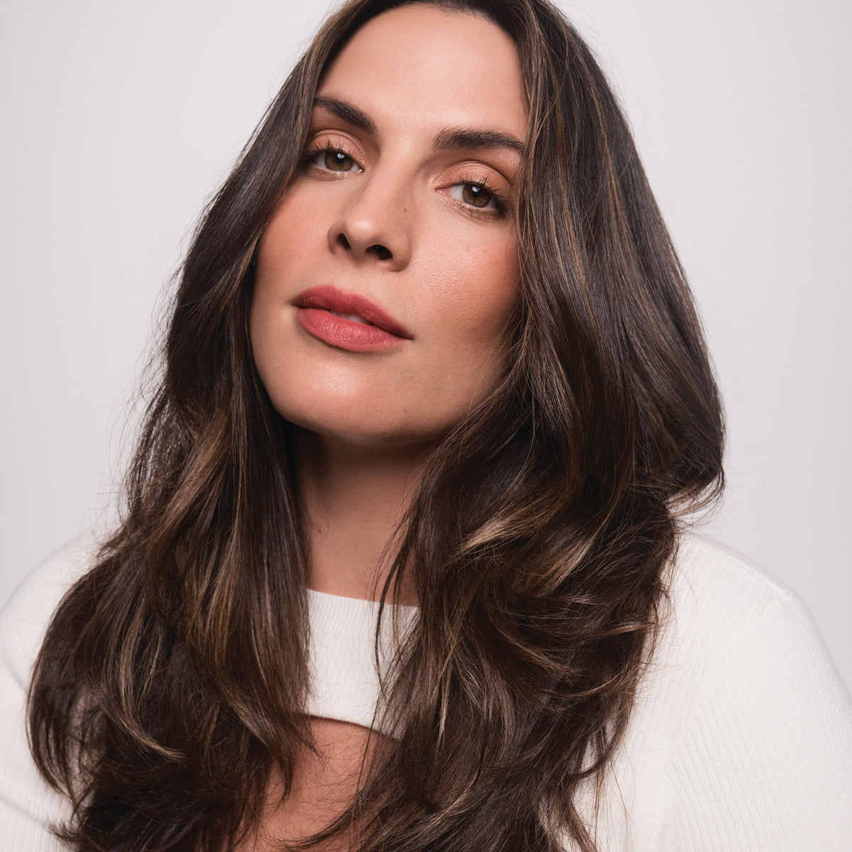 Eine Frau mit langem braunem voluminösem Haar, gestylt mit der Living Proof Full Thickening Blow-Dry Cream.