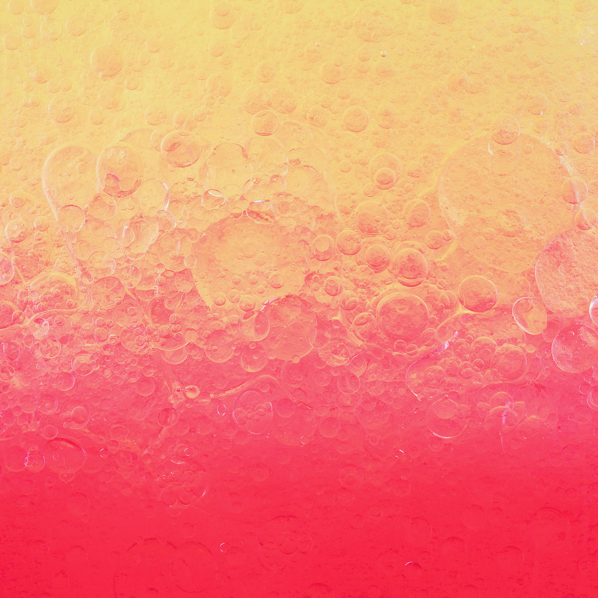 Die Nahaufnahme von Lumene NORDIC-C [VALO] Arctic Berry Multivitamin Cocktail Oil zeigt gelbe und rosafarbene Flüssigkeiten mit Blasen, die sich vermischen und einen Farbverlauf bilden.