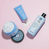 Drei blaue maria nila Coils & Curls Produkte für Locken auf rosafarbenem Hintergrund.