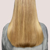 Eine Person mit langem, glattem, glänzendem blondem Haar - dank maria nila Pure Volume Conditioner -, von hinten.