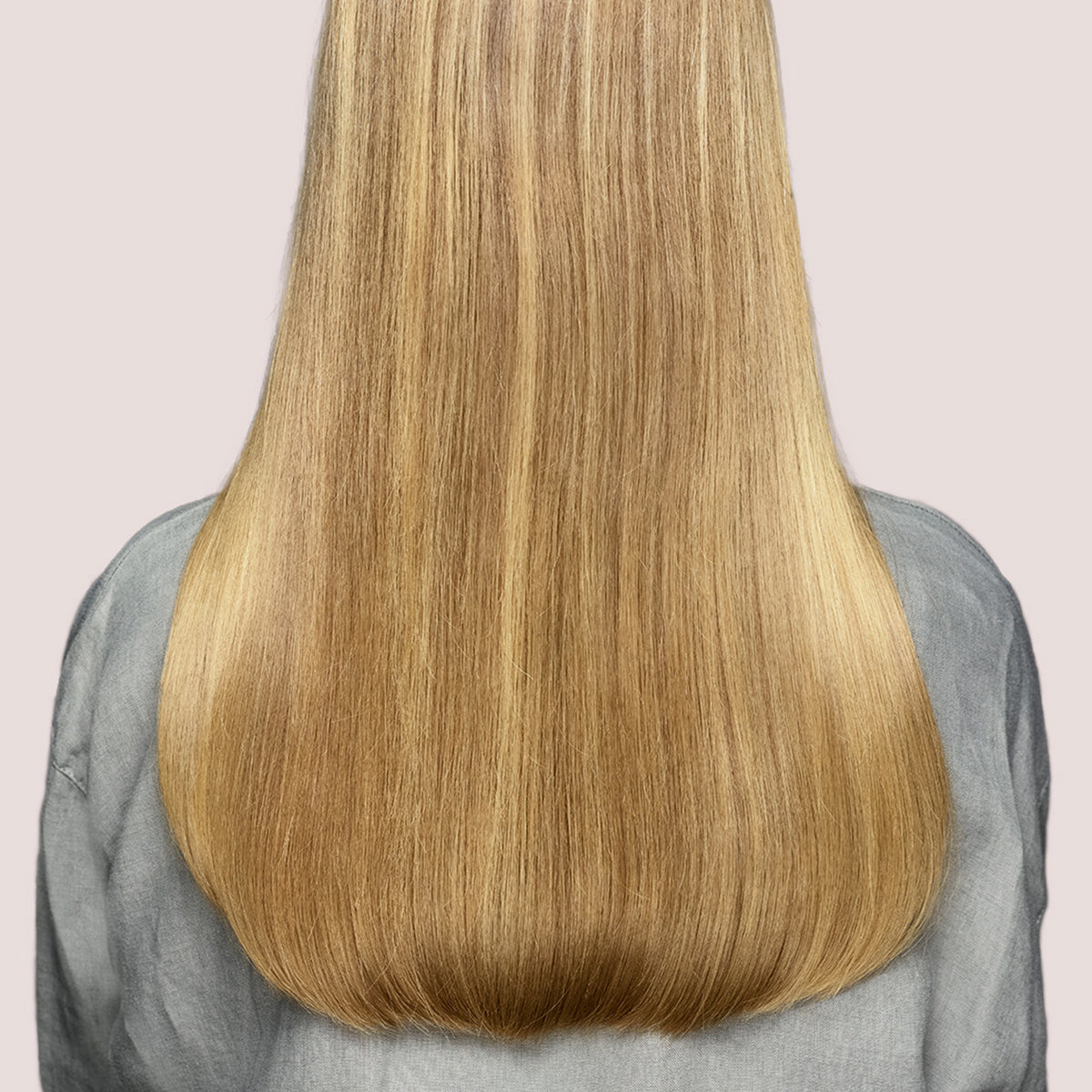Eine Person mit langem, glattem, glänzendem blondem Haar - dank maria nila Pure Volume Conditioner -, von hinten.