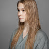 Eine junge blonde Frau präsentiert langes, nasses Haar nach Anwendung des Sheer Silver Shampoo von maria nila.