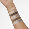 Ein innerer Unterarm zeigt sechs Swatches der Bare Harmony 2.0 Lidschattenfarben von Mesauda Beauty, die neutrale und metallische Töne enthalten.
