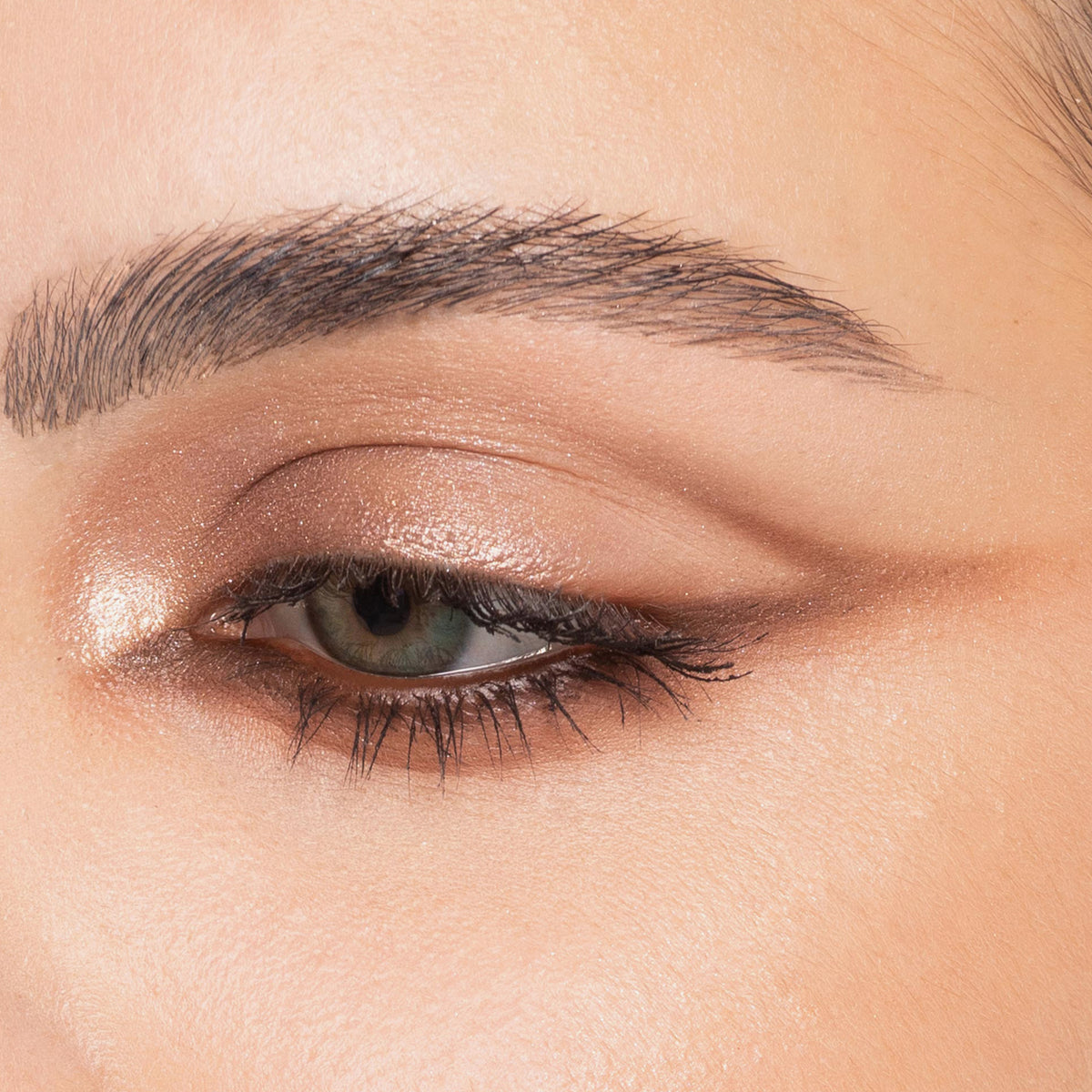 Nahaufnahme eines Auges mit schimmerndem braunem Lidschatten, geflügeltem Liner und definierten Augenbrauen, kreiert mit der Bare Harmony 3.0 Palette von Mesauda Beauty.
