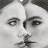 In einem Schwarz-Weiß-Porträt stehen sich zwei Frauen mit ähnlichen Gesichtszügen gegenüber und zeigen die Mascara Femuline™ by Mesauda Beauty.