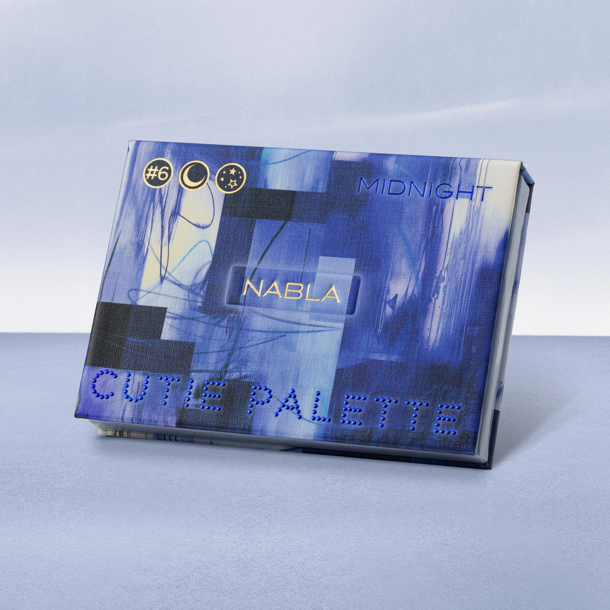 Die Cutie Palette Lidschattenbox in Blau steht auf einer hellblauen Oberfläche mit passendem Hintergrund.