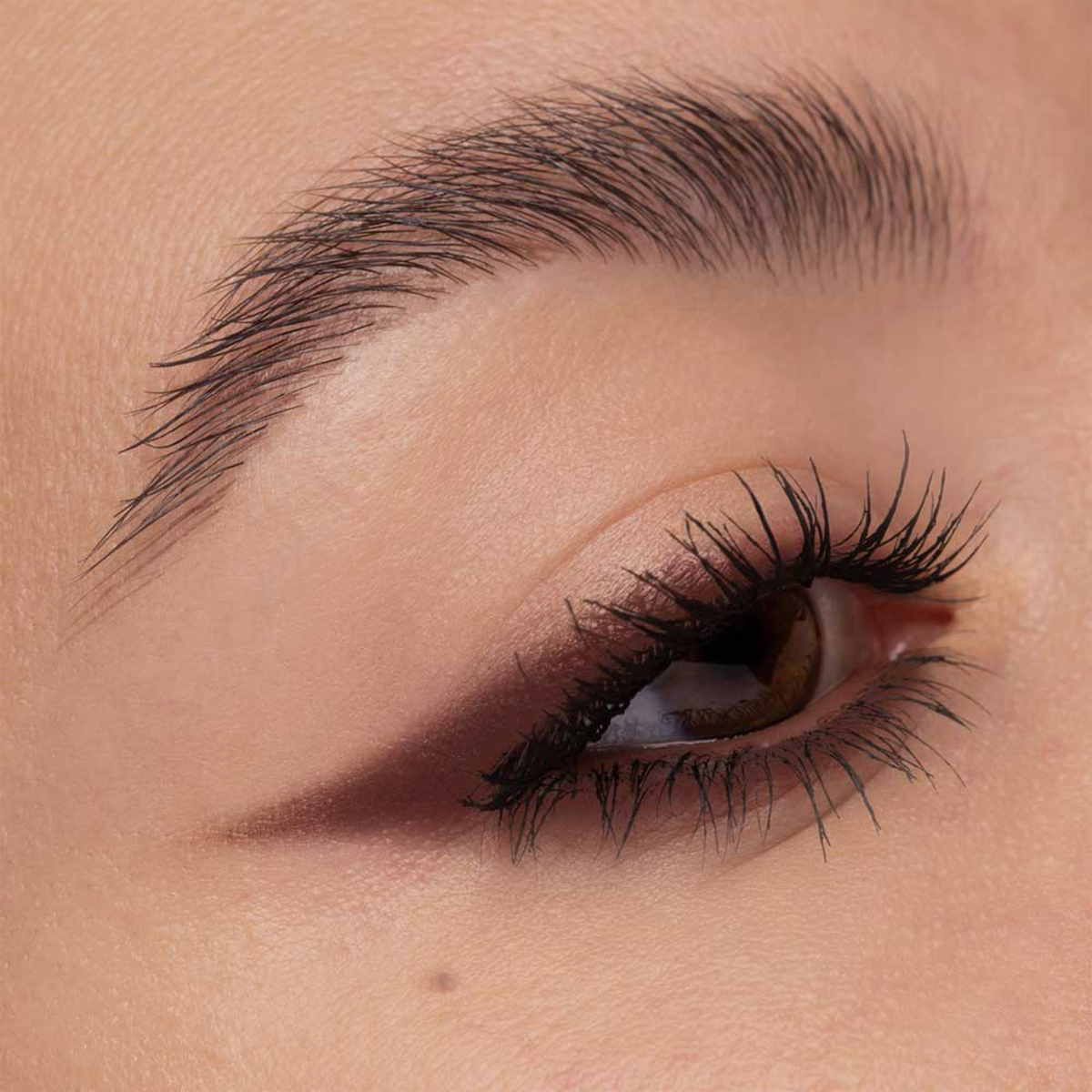 Nahaufnahme eines Auges mit langen Wimpern und scharf umrandetem braunem Lidschatten, kreiert mit NABLA Cosmetics Cupids Arrow Longwear Stylo.