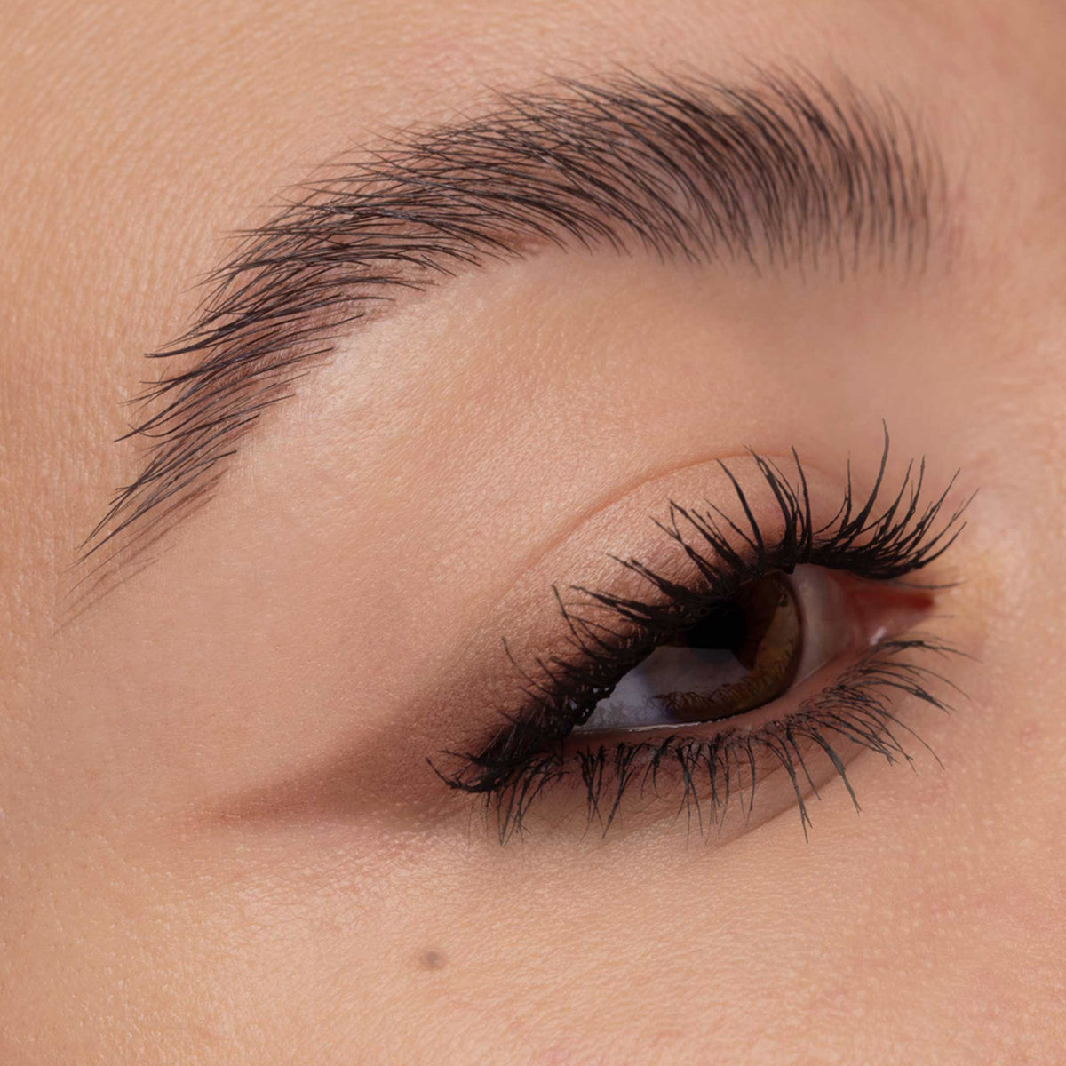 Nahaufnahme eines geschminkten Auges mit weichem, braunem Lidschatten in Cat-Eye-Form und betonten, schwarz getuschten Wimpern.