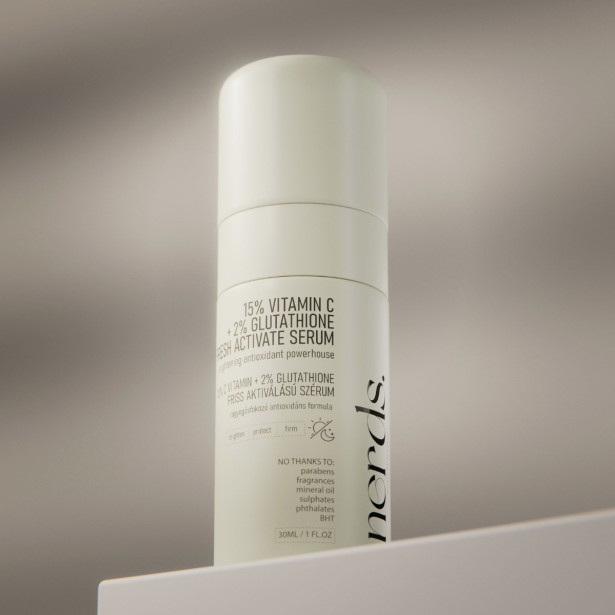 Eine weiße Flasche mit NERDS. 15% Vitamin C + 2% Glutathion Fresh Active Serum auf einer hellen Oberfläche.