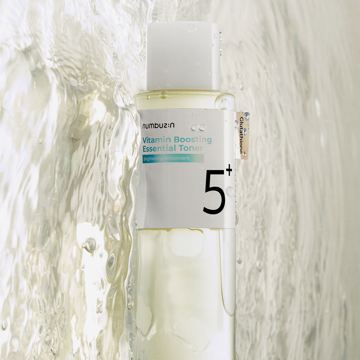 Numbuzin Nr. 5+ Vitamin Boosting Essence Toner, 200 ml, durchsichtige Flasche mit Wassertropfen auf einer nassen Oberfläche.