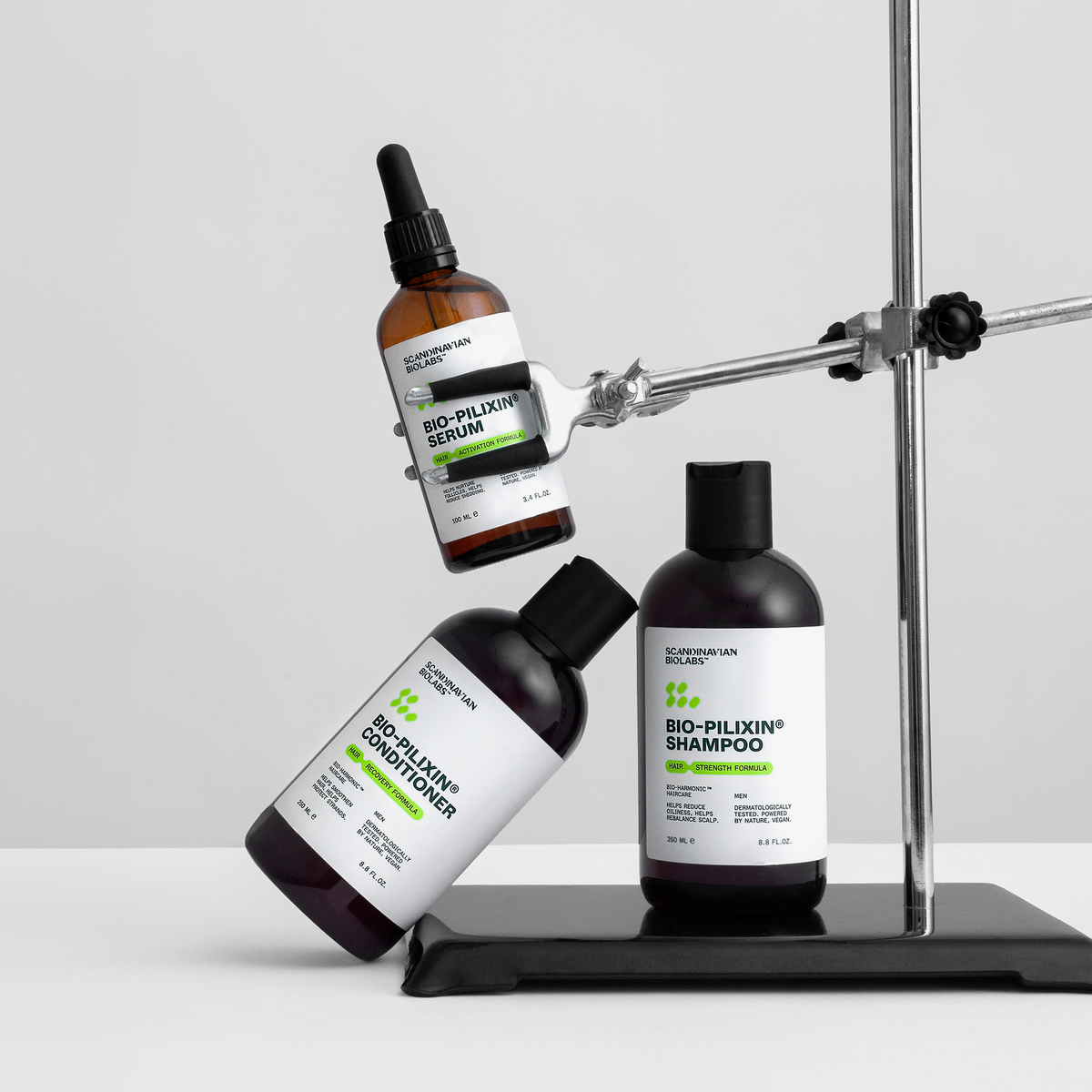 Drei Bio-Pilixin® Hair Activation Routine - Men Produkte von Scandinavian Biolabs werden mit einem Laborständer auf einer weißen Fläche präsentiert.
