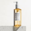 Die Flasche „Madagascar Centella Light Cleansing Oil“ steht auf einer weißen strukturierten Oberfläche.