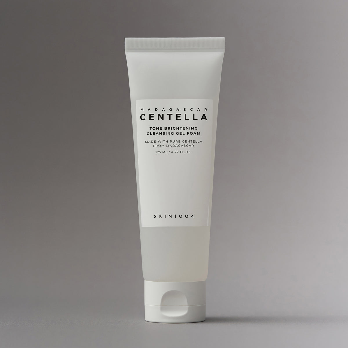 Auf grauem Hintergrund ist eine weiße Tube Madagascar Centella Tone Brightening Cleansing Gel Foam abgebildet.