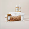Skin1004 Madagascar Centella Travel Kit mit fünf Pflegeprodukten in Reisegrößen vor dekorativer Box mit Landschaftsbild, auf hellem Hintergrund arrangiert.