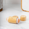Der geöffnete Bamboo Volcanic Oil Absorbing Roller wird auf einer weißen Oberfläche neben einem Spiegel platziert.