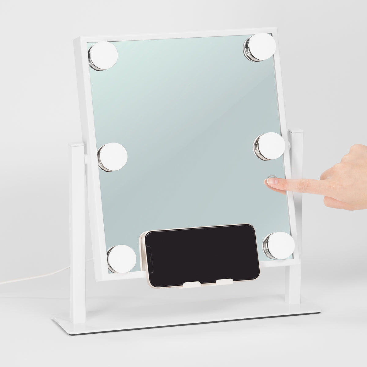 Der Glam & Groove Hollywood Bluetooth Mirror ist ein berührungsaktivierter Kosmetikspiegel mit LED-Leuchten und einer Telefonhalterung auf einem weißen Ständer.