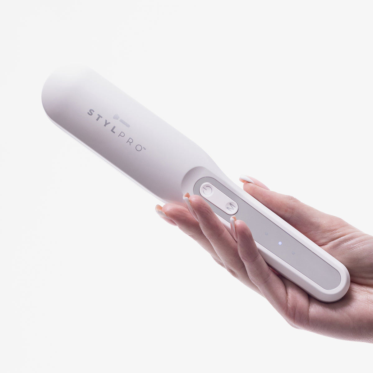 Eine Hand hält die STYLPRO Re-Growth Red Light Hair Brush, ein weißes elektronisches Gerät mit Tasten und Kontrollleuchten.